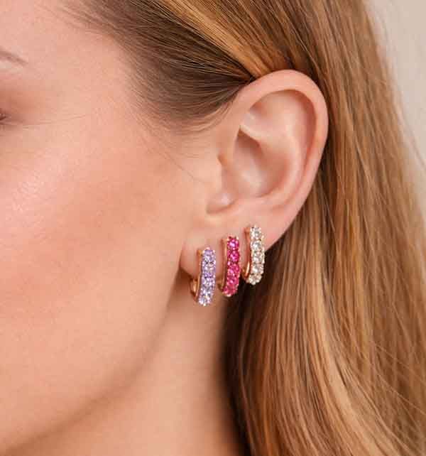 Pendientes tennis en oro rosa con circonitas lila, fucsia y blancas colocados en la oreja en combinación triple
