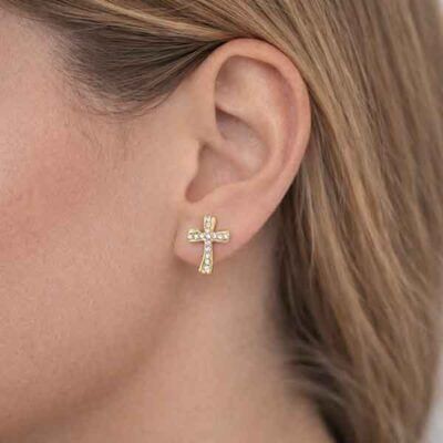 Pendientes cruz ondulada con circonitas blancas bañados en oro en oreja de modelo