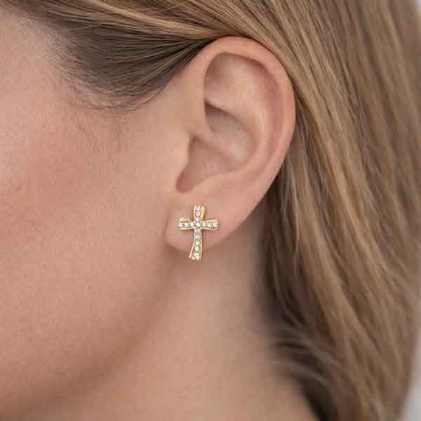 Pendientes cruz ondulada con circonitas blancas bañados en oro en oreja de modelo