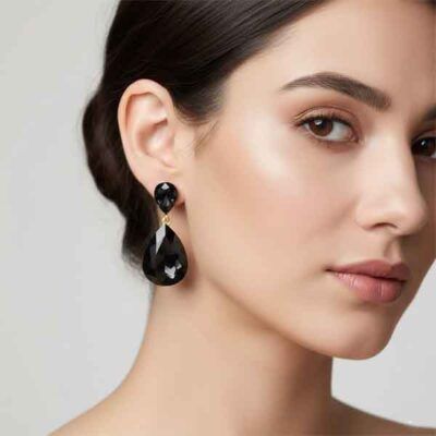 Modelo con pendientes lágrima cristal negro facetado con acabado dorado para evento