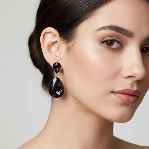 Modelo con pendientes lágrima cristal negro facetado con acabado dorado para evento