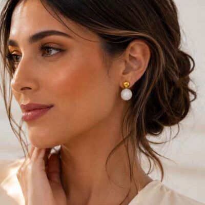 Modelo luciendo pendientes Avihe dorados con esfera de circonitas brillantes