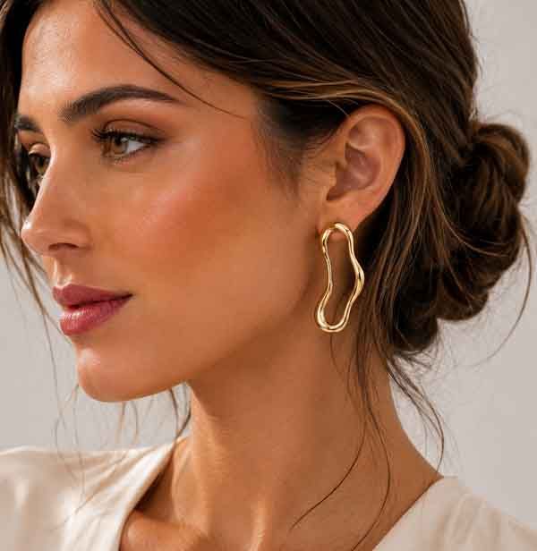 Modelo luciendo pendientes Dravor dorados de Luxenter con diseño orgánico moderno