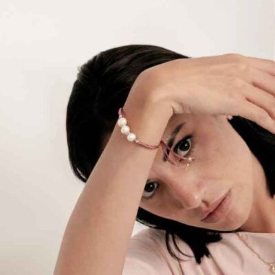 Modelo luciendo la Pulsera Melmay de Luxenter con perlas blancas y cordón rosa