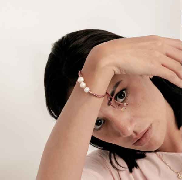 Modelo luciendo la Pulsera Melmay de Luxenter con perlas blancas y cordón rosa