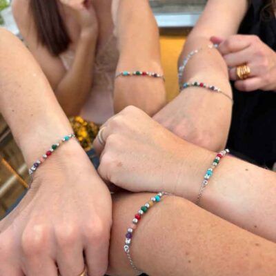 Cinco amigas luciendo una pulsera personalizada con historia creada artesanalmente por Turquesa y Más como recuerdo de un viaje especial.