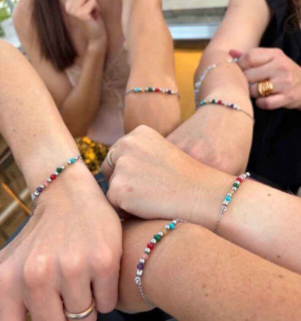 Cinco amigas luciendo una pulsera personalizada con historia creada artesanalmente por Turquesa y Más como recuerdo de un viaje especial.